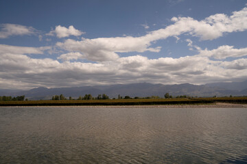 View of the artificial lake, vineyard and mountains in the horizon. Beautiful blue sky reflection in the water surface.