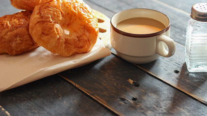 Croissant served with coffee on a black wooden table.