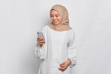 Smiling young Asian Muslim woman using a mobile phone, received good news isolated over white background