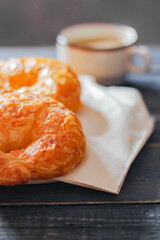 Croissant served with coffee on a black wooden table.