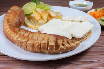 Typical Colombian food, chocolo arepa with cheese, pork chicarron French fries, chimichurri and salad