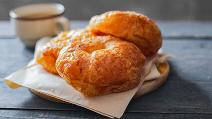Croissant served with coffee on a black wooden table.
