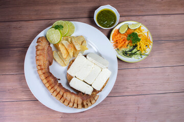 Typical Colombian food, chocolo arepa with cheese, pork chicarron French fries, chimichurri and salad