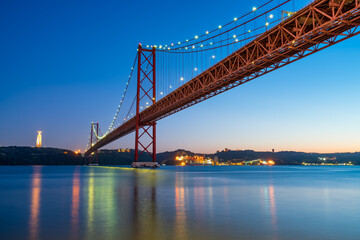 Fototapeta na wymiar The 25 de Abril bridge over the Tajo River with Cristo Rei or Christ the King in the background. Lisbon. Portugal