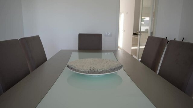 A glass table with a vase and a plate in the living room for dinner guests in a modern style and leather chairs.
