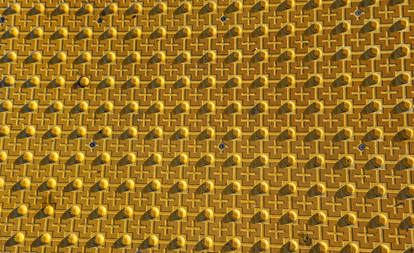Textured yellow metal surface with bumps, crosses, honeycomb pattern, distinctive background for conceptual messages.