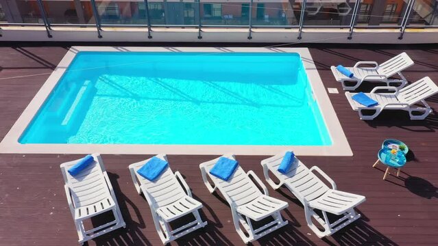 Luxury pool on the roof of the house with sun loungers and towels for tourists to relax with clear blue water. Infrastructure luxury concept of the future.