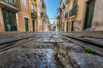 Fototapeta na wymiar Tram tracks at the narrow street in the Lisbon, a detail metal rails for the tram