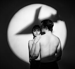 the shadow of the silhouette of a rocket bomb on a pair of peaceful young people on a white...
