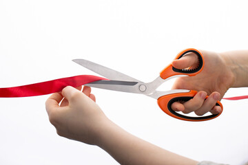 Cutting a red ribbon with scissors on a white background. Opening procedure, inauguration, new project.