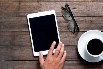 Hand holding and touching on tablet screen / on a wooden desk