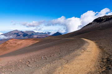 Fototapeta na wymiar A hiking trail curves into the landscape of a barren, colorful volcanic crater at Sliding Sands Trail, Haleakala National Park, Maui