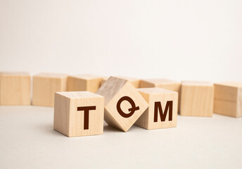 TQM, TEXT on wood cubes on a light background