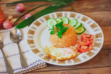 Fried Rice with Fried Egg Put on the wooden table and the tomatoes, cucumbers, garlic, shallots