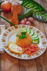 Fried Rice with Fried Egg Put on the wooden table and the tomatoes, cucumbers, garlic, shallots