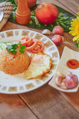 Fried Rice with Fried Egg Put on the wooden table and the tomatoes, cucumbers, garlic, shallots