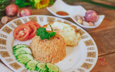 Fried Rice with Fried Egg Put on the wooden table and the tomatoes, cucumbers, garlic, shallots