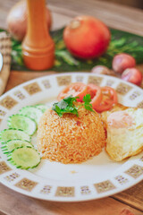 Fried Rice with Fried Egg Put on the wooden table and the tomatoes, cucumbers, garlic, shallots