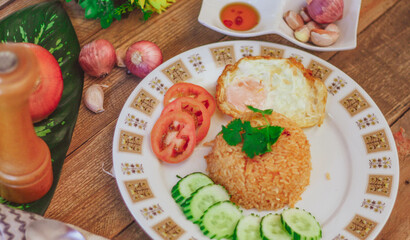 Fried Rice with Fried Egg Put on the wooden table and the tomatoes, cucumbers, garlic, shallots