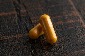 Ground Turmeric Capsules form on a Wooden Table