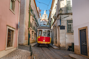 Traditional tram 28 crossing narrow streets of Lisbon. Portugal
