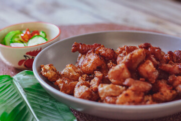 Fried Pork Belly with Fish Sauce and Sticky Rice Served on a white plate on a black wooden floor.