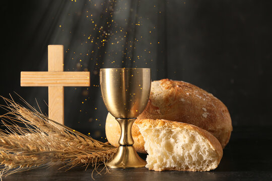 Chalice of wine with bread and cross on dark background. Holy Communion concept