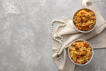 Bowls of tasty Asian pilaf and tasbih on grunge background