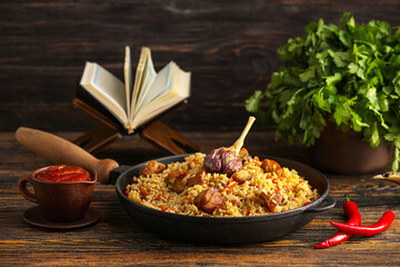 Frying pan with tasty Asian pilaf on table