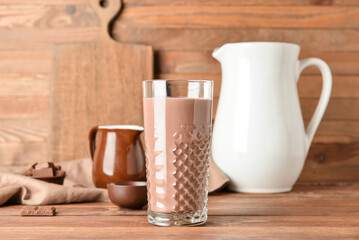 Glass of delicious chocolate milk on wooden background