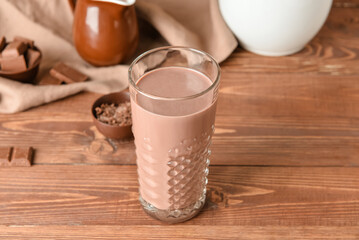 Glass of delicious chocolate milk on wooden background