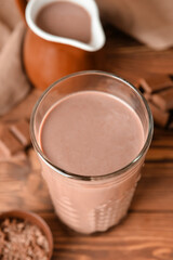 Glass of delicious chocolate milk on wooden background, closeup