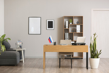 Interior of stylish office with Russian flag and modern laptop