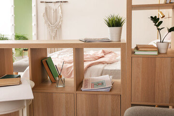 Wooden book shelf with reed diffuser and newspapers in bedroom