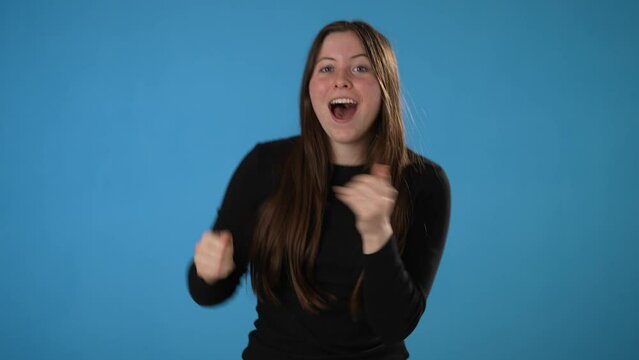 Happy young woman 20s dancing waving rising expressive gesticulate hands fool around have fun celebrate play fluttering hair isolated on blue background