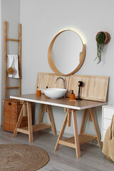 Interior of light bathroom with table, sink and mirror