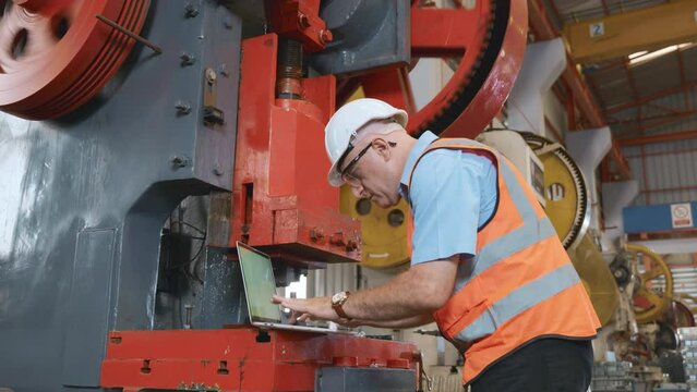 Factory worker using a laptop with an engineering software, Engineer using laptop computer controlling program for maintenance automatic to metal sheet stamping machine, industry programer man