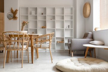 Interior of light dining room with table, shelving unit and armchair