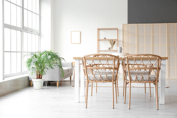 Interior of light dining room with table, sofa and folding screen