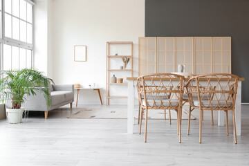 Interior of light dining room with table, sofa and folding screen