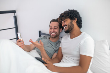 Fototapeta premium Cheerful man pointing at his cellphone screen to his boyfriend