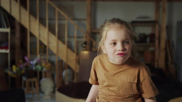 The child makes funny faces and wrinkles while singing a song