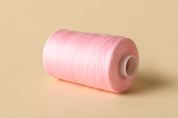 Pink sewing thread spool on light background