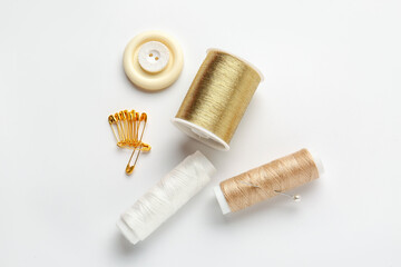 Thread spools with buttons and pins on white background