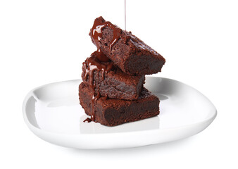 Pouring of chocolate topping onto plate with tasty brownies on white background