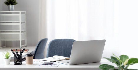 Laptop computer and document on wooden table in modern office room.