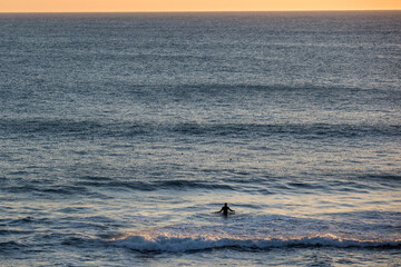 Surfer waits in the water to ride a wave, in the Pacific ocean along the California Coast in the United States.