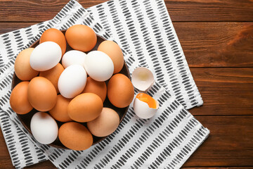 Plate with chicken eggs on wooden background