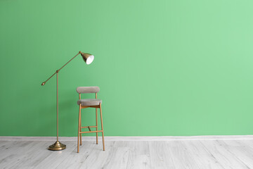 Stylish chair and standard lamp near green wall