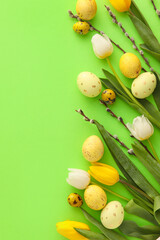 Painted Easter eggs, tulip flowers and willow branches on green background